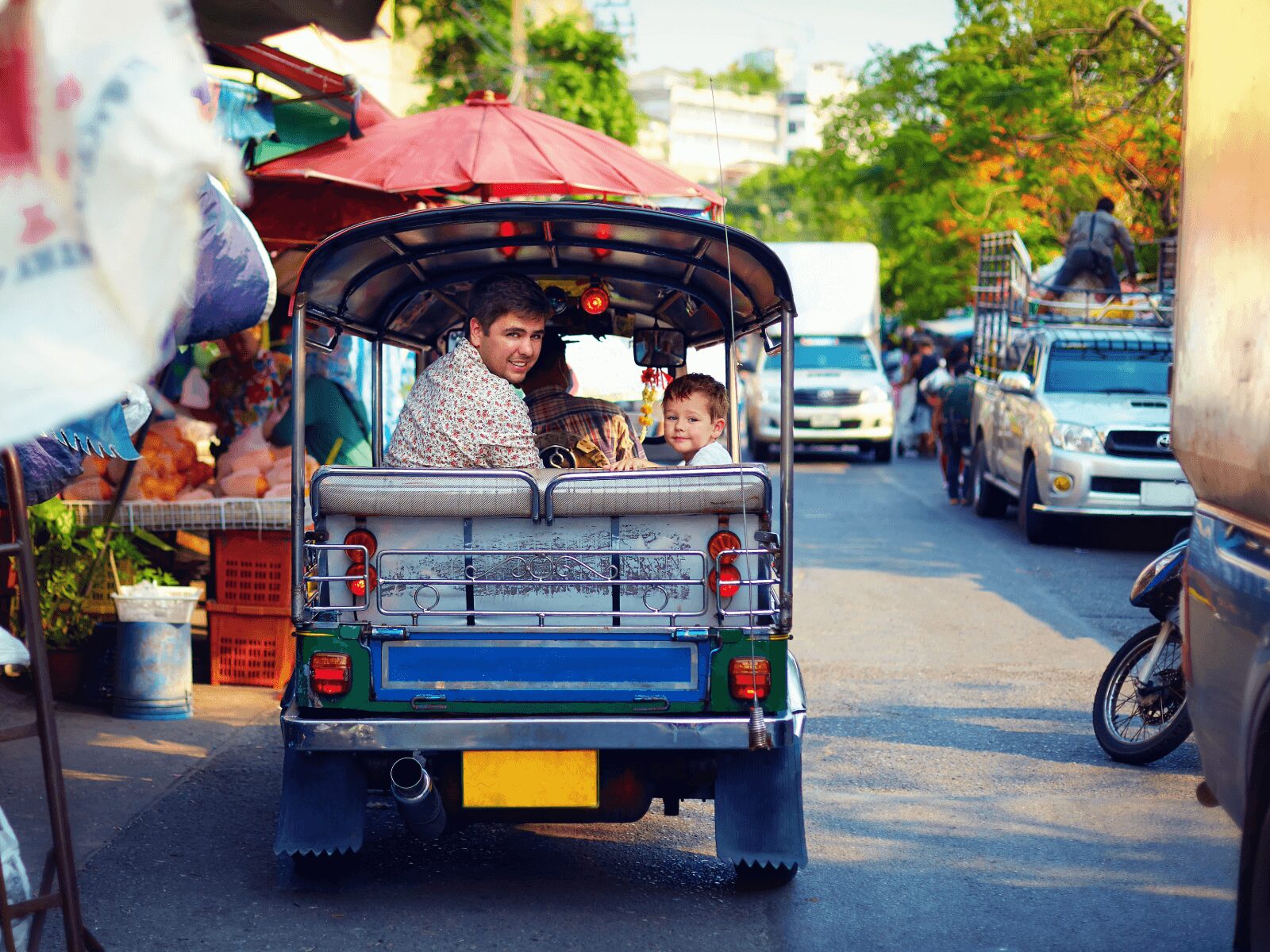 Happy family travel through the asian city on tuk-tuk taxi
